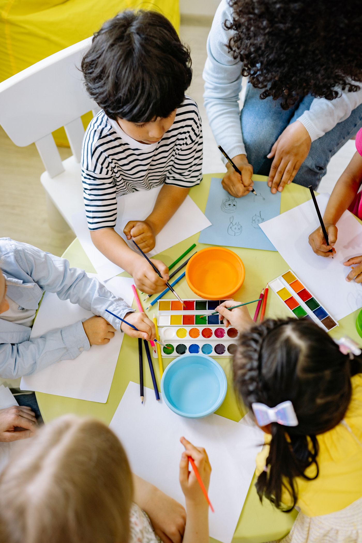 Overhead view of an adult and children working with colors at a table