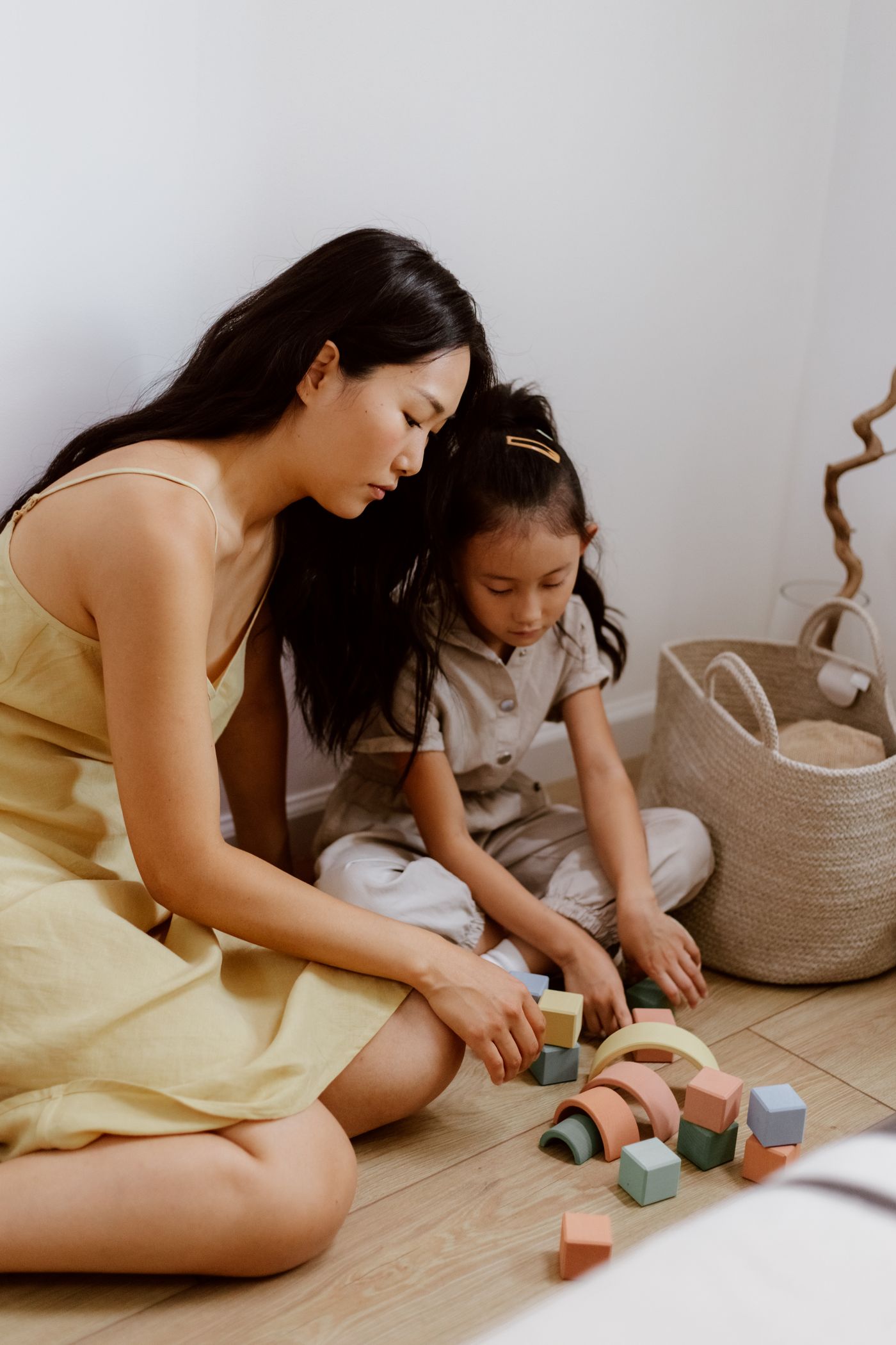 A mother and her young daughter playing together with wooden building blocks at home